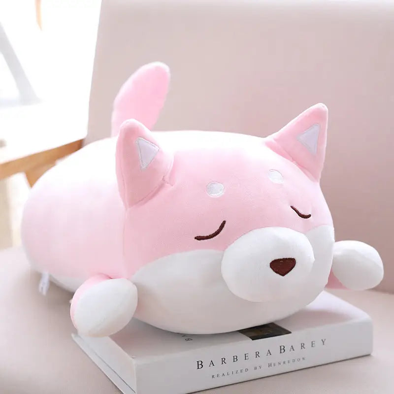 Peluche Shiba Inu rose, douce et kawaii, idéale pour enfants et bébés, reposant sur un livre.